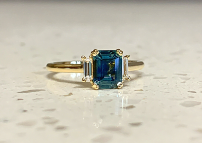 Luxury custom yellow gold teal sapphire emerald-cut ring, handcrafted in Leduc, AB